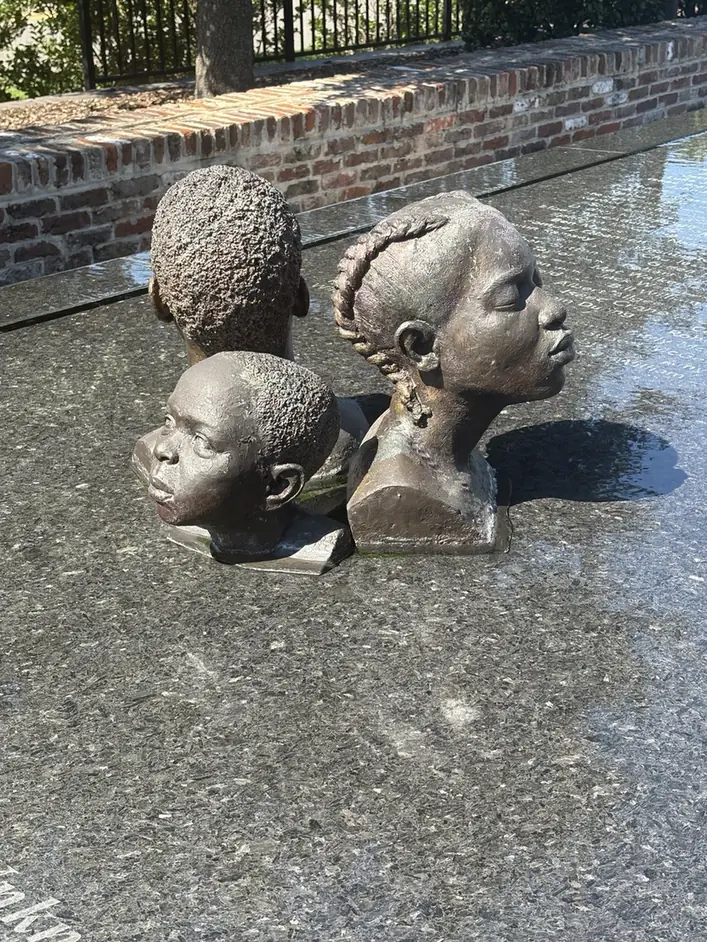 Sculpted heads in a reflective memorial installation.